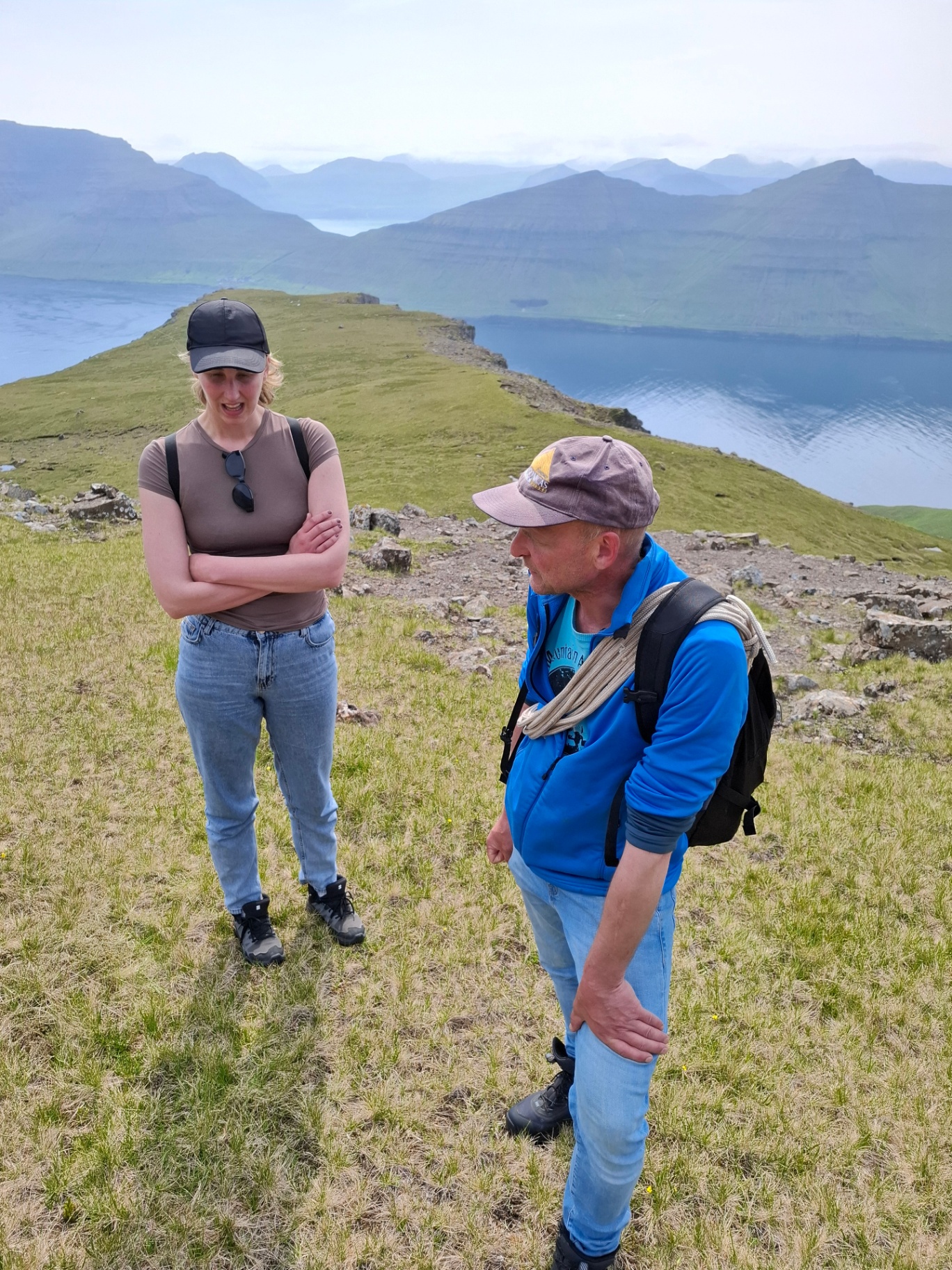 A Faroese landowner talking with a hiker on a green headland