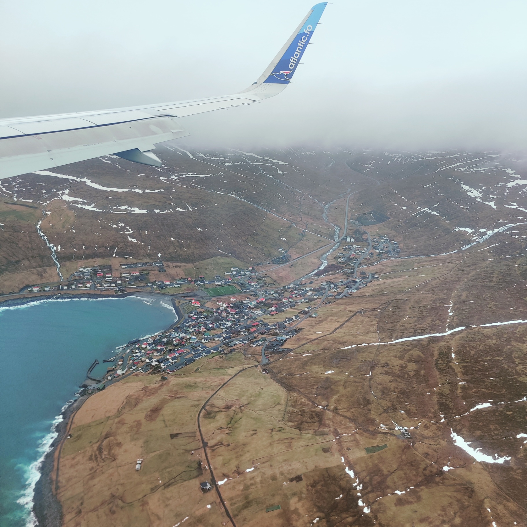 A Faroese village of turf-roofed and painted houses spread along a valley between mountain and sea