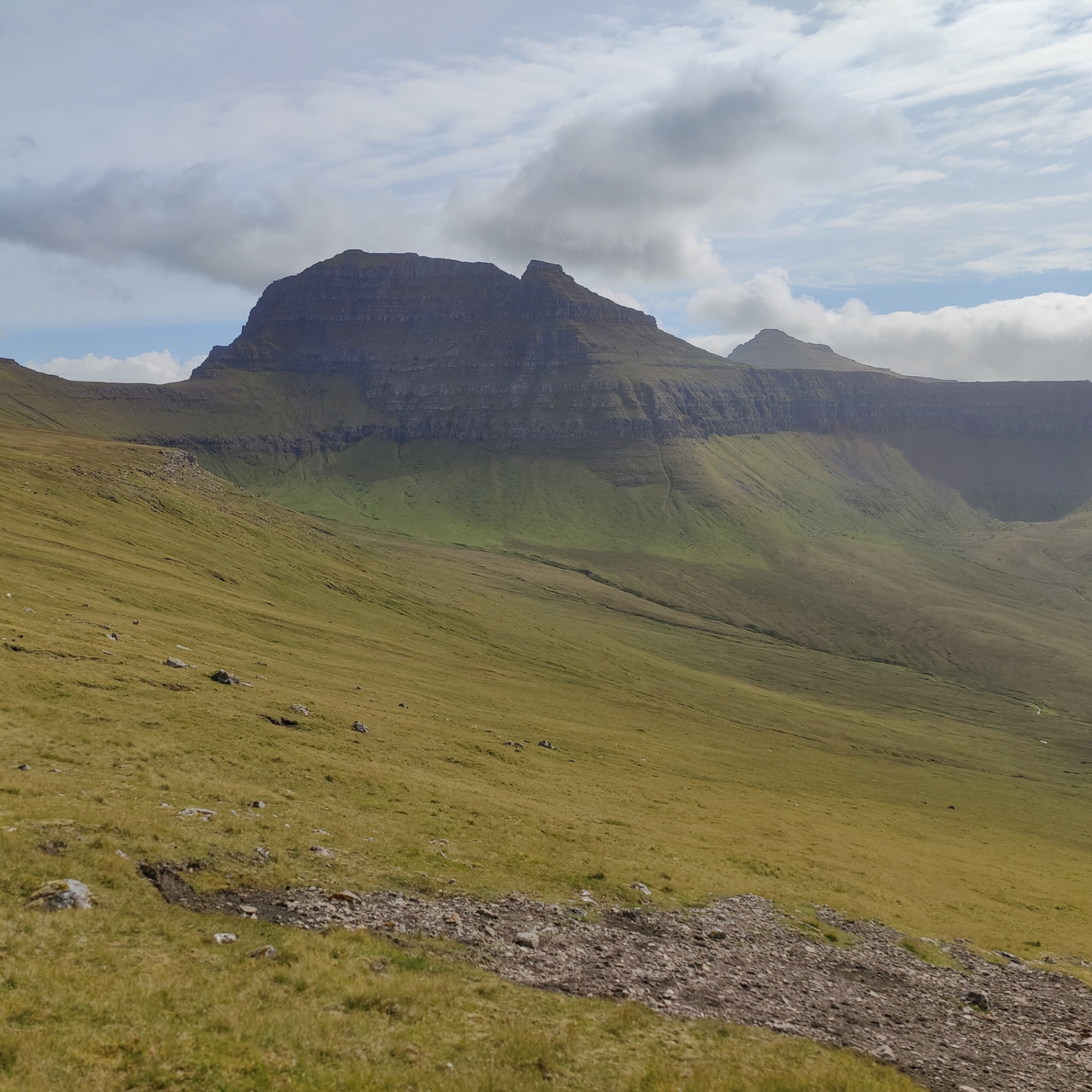 A flat-topped Faroese mountain of layered basalt terraces above a green valley